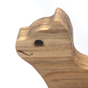 A freestanding wooden puzzle cut in the shape of a large cat standing on four legs. Two smaller kitten figures nest on the large cat’s back and interlock as puzzle pieces. Simple drilled holes form the eyes and nose on each cat, with a shallow cut line for the mouth on the large cat. The completed puzzle stands upright on a plain white surface. Handmade by Odin’s Toy Factory In Tallahassee, Florida, USA.