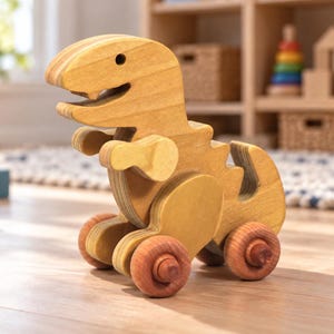 Wooden T-Rex dinosaur push toy with an oil-and-wax finish and brown wooden wheels on a wood floor in a child’s play area, with blocks, a rug, and toy storage shelves softly blurred behind it.
