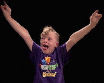 Camiseta infantil roxa "Play Like a Rockstar" com símbolos de comunicação.