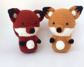 May include: Two crocheted fox plushies, one red and one orange, with white accents and black eyes.