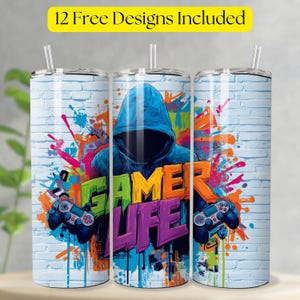 May include: Three stainless steel tumblers with straws, featuring a vibrant "Gamer Life" design. The design includes a hooded figure, game controllers, and colorful graffiti-style accents against a white brick background. The text "12 Free Designs Included" is at the top.