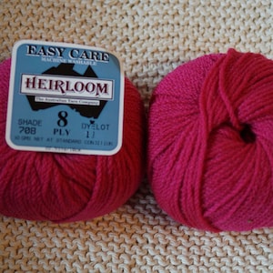 May include: Two balls of bright pink Heirloom yarn. One ball has a label that reads "Easy Care Machine Washable Heirloom". The yarn is 8 ply and shade 708. The yarn is on a beige knitted surface.