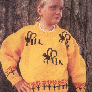 May include: A yellow knitted jumper with a black bee design. The jumper has a crew neck and long sleeves. The sleeves have a red and black floral pattern at the cuffs.