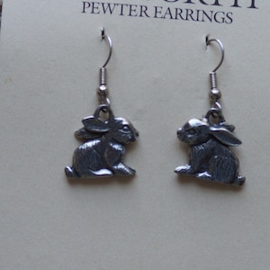 May include: A pair of pewter earrings featuring a sitting rabbit design. The earrings are silver-colored and have surgical steel posts and wires. The brand name "DANFORTH" and "PEWTER EARRINGS" are printed on the card.