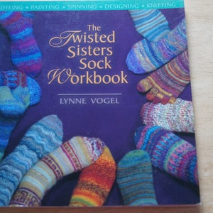 May include: The Twisted Sisters Sock Workbook by Lynne Vogel, a book cover featuring a purple background with colorful knitted socks arranged in a circle.