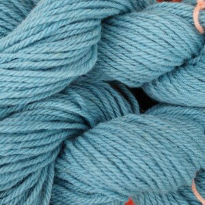 May include: Close-up of a skein of teal blue yarn. The yarn is soft and fluffy, and it is perfect for knitting or crocheting.