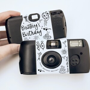May include: Two black disposable cameras with white labels featuring the text "Brittney's Birthday" and decorative doodles. One camera displays the number "30". The phrase "Turn on the flash" is also visible.