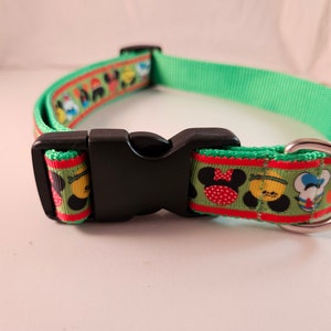 Peut inclure: Un collier de chien vert avec une boucle noire et un anneau en D argenté. Le collier est décoré d'un ruban rouge et vert avec des personnages de dessins animés.