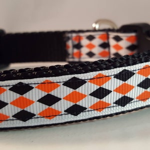 May include: Black and orange diamond patterned dog collar with a black buckle.