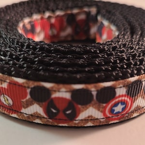 Könnte beinhalten: Schwarz-weiß gemustertes Hundehalsband mit roten, blauen und schwarzen Superhelden-Charakterbildern. Das Halsband ist aus strapazierfähigem Nylon.