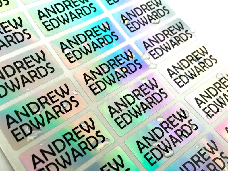 May include: A sheet of rectangular adhesive labels featuring a holographic finish that shifts between green, blue, and silver tones. Each individual label is printed with the name Andrew Edwards in a bold, black, sans-serif capital font.