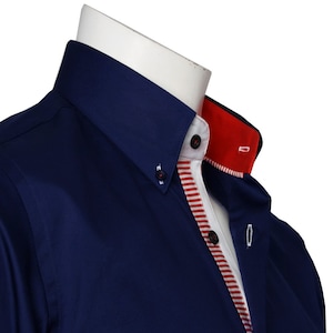 Puede incluir: Una camisa azul marino de vestir con cuello blanco y ribete rojo. La camisa tiene cuello abotonado y un solo botón de cierre.