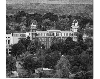 May include: A black and white photograph of a brick building with a clock tower. The building is surrounded by trees and is set against a backdrop of a rolling hillside.
