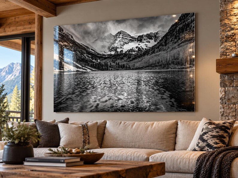 May include: A large rectangular wall art print featuring a black and white landscape photograph of the Maroon Bells mountains reflected in a calm lake, with snow-capped peaks, dense forest slopes, and rippled water surface textures.