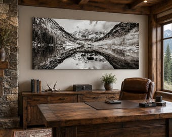 May include: A large, rectangular, black and white panoramic wall art print depicting a mountain range reflected in a calm lake. The landscape features snow-capped peaks, dense evergreen forests, and rocky terrain, creating a symmetrical composition.