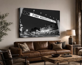 May include: A black and white wall art print featuring the Fort Worth Stock Yards sign spanning across a street at night. The image captures the illuminated signage and the surrounding historic buildings in a high-contrast monochromatic style.