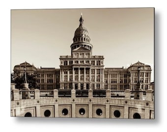 May include: A black and white photograph of the Texas State Capitol building in Austin, Texas. The building is a large, ornate structure with a dome and a tall tower. The building is surrounded by a stone fence and a grassy lawn.