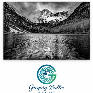 May include: A black and white landscape photograph of a lake reflecting snow-capped mountains under a cloudy sky. Below the image is a circular logo featuring a stylized letter G and the text Gregory Ballos FINE ART.