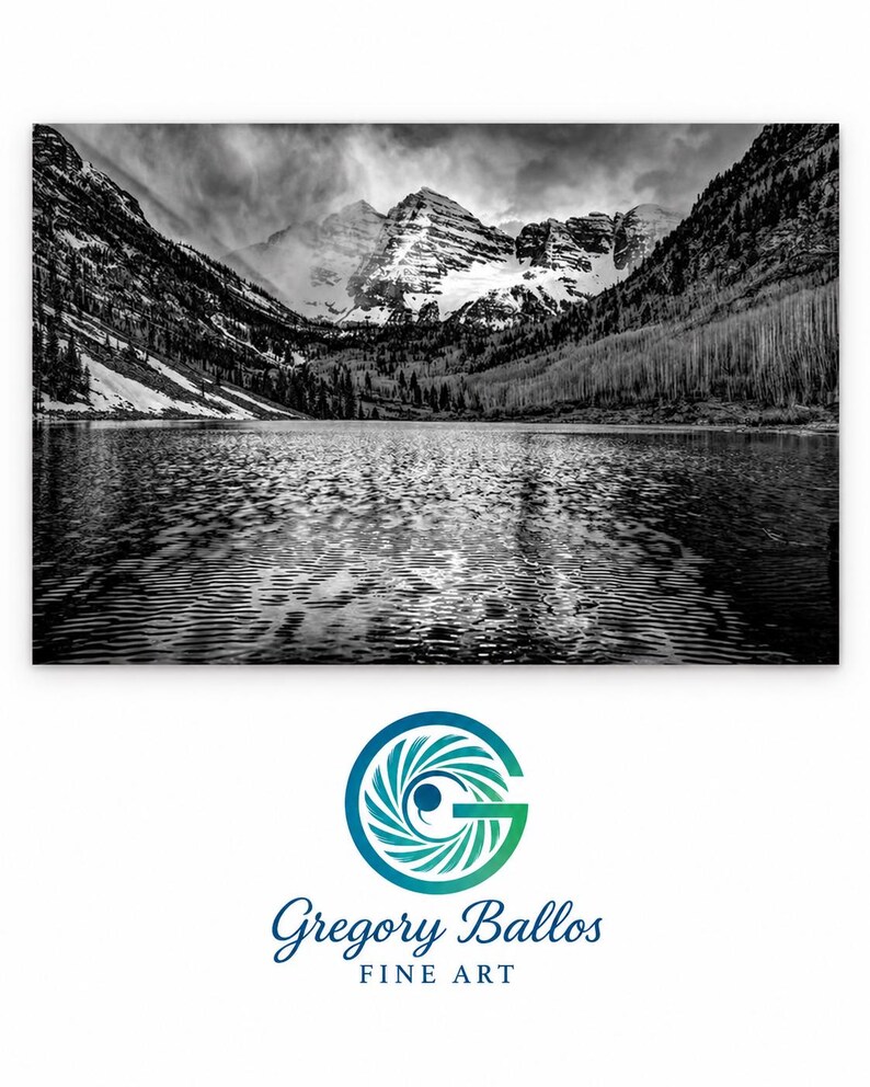 May include: A black and white landscape photograph of a lake reflecting snow-capped mountains under a cloudy sky. Below the image is a circular logo featuring a stylized letter G and the text Gregory Ballos FINE ART.