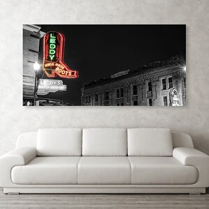 May include: Black and white photograph of a building with a neon sign that reads "Leddy's Hand Made Boots". The sign is shaped like a boot and is lit up in red and green.