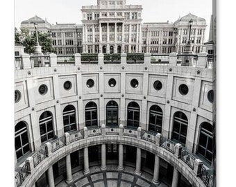 May include: A black and white photo of the Texas State Capitol building in Austin, Texas. The photo is taken from inside a circular building with a star-shaped design on the floor.
