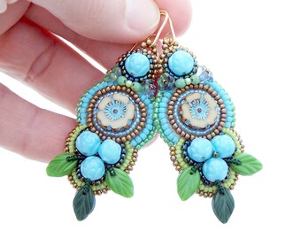 May include: A pair of blue, green, and gold beaded earrings with a floral design. The earrings are made with small beads and have a delicate, feminine look.