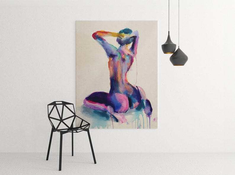Large abstract watercolor nude painting by Nick Horvath displayed in a modern minimalist room with geometric black chair and pendant lights. Features a kneeling female figure in bold purples, pinks, and blues with expressive drips. Striking, sensual wall art.