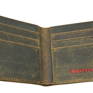 Pu&ograve; includere: Un portafoglio in pelle marrone con pi&ugrave; slot per carte e un portafoglio per banconote. Il portafoglio &egrave; aperto e l'interno &egrave; visibile. Il nome del marchio "BallPark Leather" &egrave; stampato in rosso sul lato destro del portafoglio.