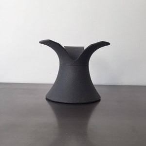 May include: A black, ceramic, pedestal stand with a wide, flared base and a narrow, three-pronged top.