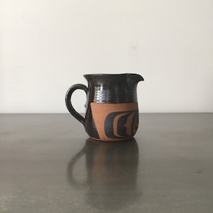 Peut inclure: Un pichet en céramique brun avec un motif géométrique dans les tons de brun et de noir.