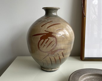 Könnte beinhalten: Eine Keramikvase mit brauner und grüner Glasur. Die Vase hat einen runden Körper und einen schmalen Hals. Sie ist mit einem braunen abstrakten Muster verziert.