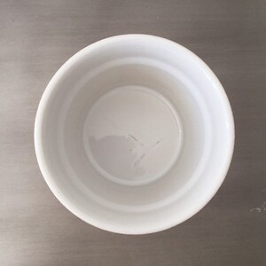 May include: A white ceramic ramekin with a smooth, slightly textured surface. The ramekin is empty and appears to be new.