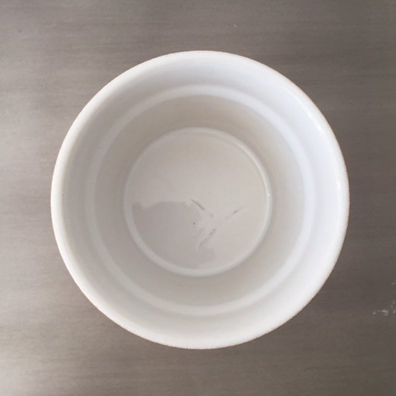 May include: A white ceramic ramekin with a smooth, slightly textured surface. The ramekin is empty and appears to be new.