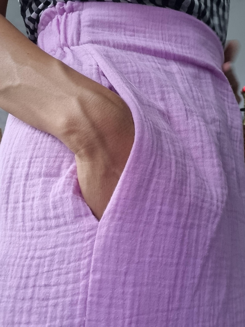 May include: A light purple skirt with a textured, crinkled fabric. The skirt has a wide waistband and a deep pocket. The fabric appears to be lightweight and breathable, suitable for warm weather. The skirt is a solid color.