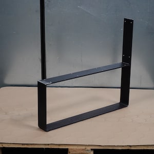 Pu&ograve; includere: Gambe da tavolo in metallo nero con forma rettangolare e un solo ripiano. La gamba &egrave; appoggiata su un pallet di legno.