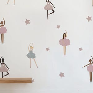 May include: A white wall with a repeating pattern of pink and blue ballerinas and brown stars. A wooden shelf is mounted on the wall. A brown woven rug is on the floor.