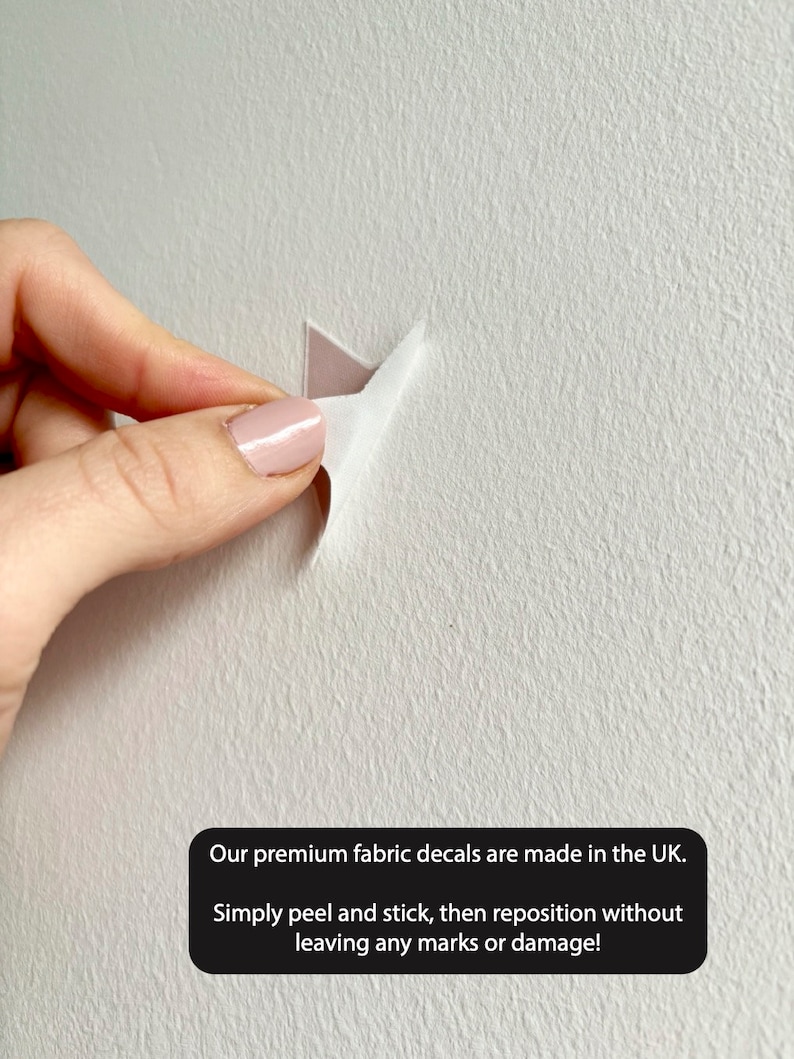 May include: A hand peeling back a corner of a fabric decal to show the adhesive backing. The decal is being applied to a white wall. The text reads: "Our premium fabric decals are made in the UK. Simply peel and stick, then reposition without leaving any marks or damage!"