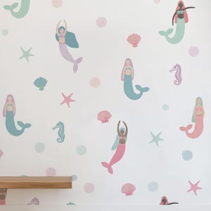 May include: A white wall decorated with colorful mermaid and sea creature decals. The mermaids have pink, blue, and purple tails and hair. Sea shells, starfish, and bubbles in pastel colors complete the underwater theme.