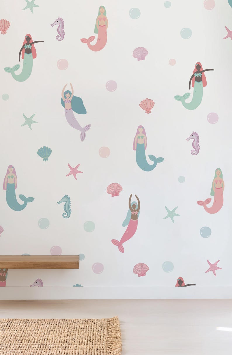 May include: A white wall decorated with colorful mermaid and sea creature decals. The mermaids have pink, blue, and purple tails and hair. Sea shells, starfish, and bubbles in pastel colors complete the underwater theme.