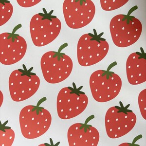 May include: A white background with a repeating pattern of red strawberries with white seeds. The strawberries have green leaves.