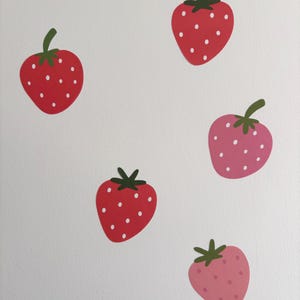 May include: Five paper cutouts of strawberries in different shades of pink and red. The strawberries have white dots and green leaves.
