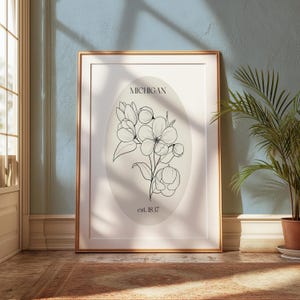 May include: A framed print with a black and white line drawing of a flower with the text "MICHIGAN est. 1837" on a cream background.