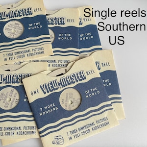 Könnte beinhalten: Eine Sammlung von Vintage View-Master-Rollen mit Szenen aus dem Süden der Vereinigten Staaten. Die Rollen sind mit den Nummern 299, 168, 331 und 161 sowie den Titeln "Hot Springs National Park, Arkansas, USA", "Silver Springs, Florida, USA", "New Orleans, Louisiana, USA" und "7 More Wonders" beschriftet. Die Rollen sind alle in gutem Zustand und haben ein blau-weiß gestreiftes Design.
