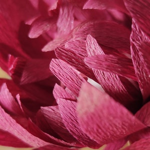 May include: Close-up of a pink paper flower with crinkled petals. The flower is made of tissue paper and has a delicate, layered texture.