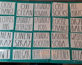 May include: A set of 16 white labels with black text, each with a different laundry-related term. The labels are arranged in four rows of four. The terms are: Loose Change, Oxi Clean, Laundry Powder, Lost Socks, All Purpose, Clothes Pins, Laundry Detergent, Laundry Pods, Loose Change, Dryer Balls, Linen Spray, Linen Spray, Laundry Booster, Baking Soda, Washing Soda, Lint, Vinegar, Dryer Sheets, Softener, Bleach.