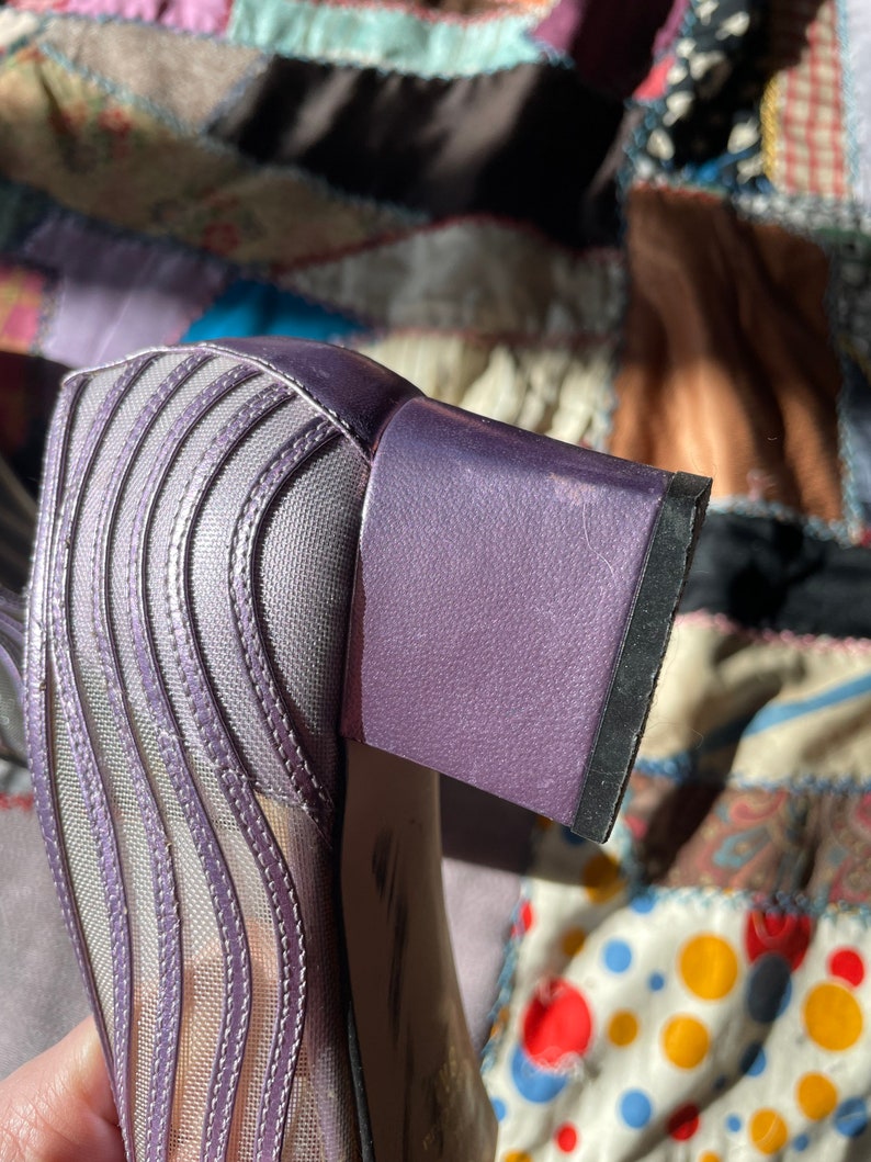 Pu&ograve; includere: Scarpe con tacco in rete viola con tacco a blocco. Il tacco &egrave; rivestito in tessuto testurizzato.
