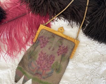 May include: Vintage gold-toned metal mesh purse with a floral design in shades of pink, green, and blue. The purse has a decorative frame and a delicate chain handle. The bottom of the purse has a unique, pointed edge.