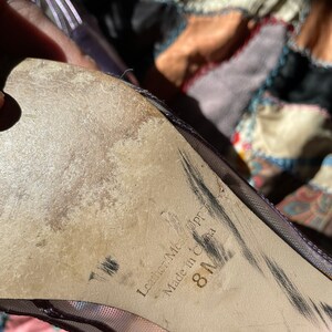 Pu&ograve; includere: Primo piano della suola di una scarpa in rete viola con il testo "Leather-Made Upper" e "Made in China" e la taglia "8 1/2".