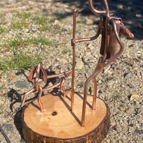 Figura artística de cobre de un excursionista con un perro