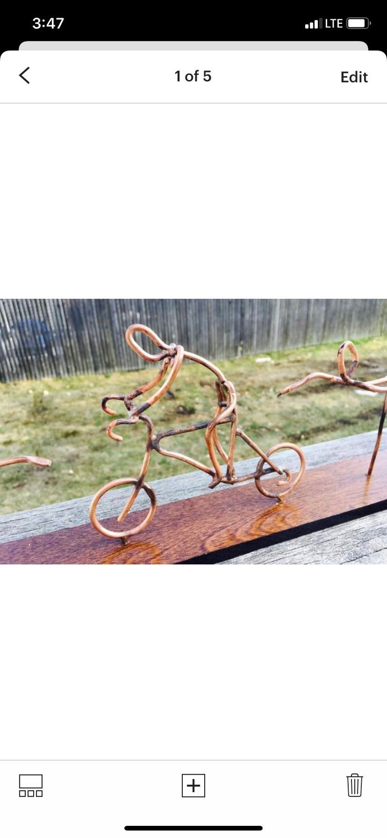 May include: A copper wire sculpture of a person riding a bicycle. The sculpture is mounted on a wooden base.